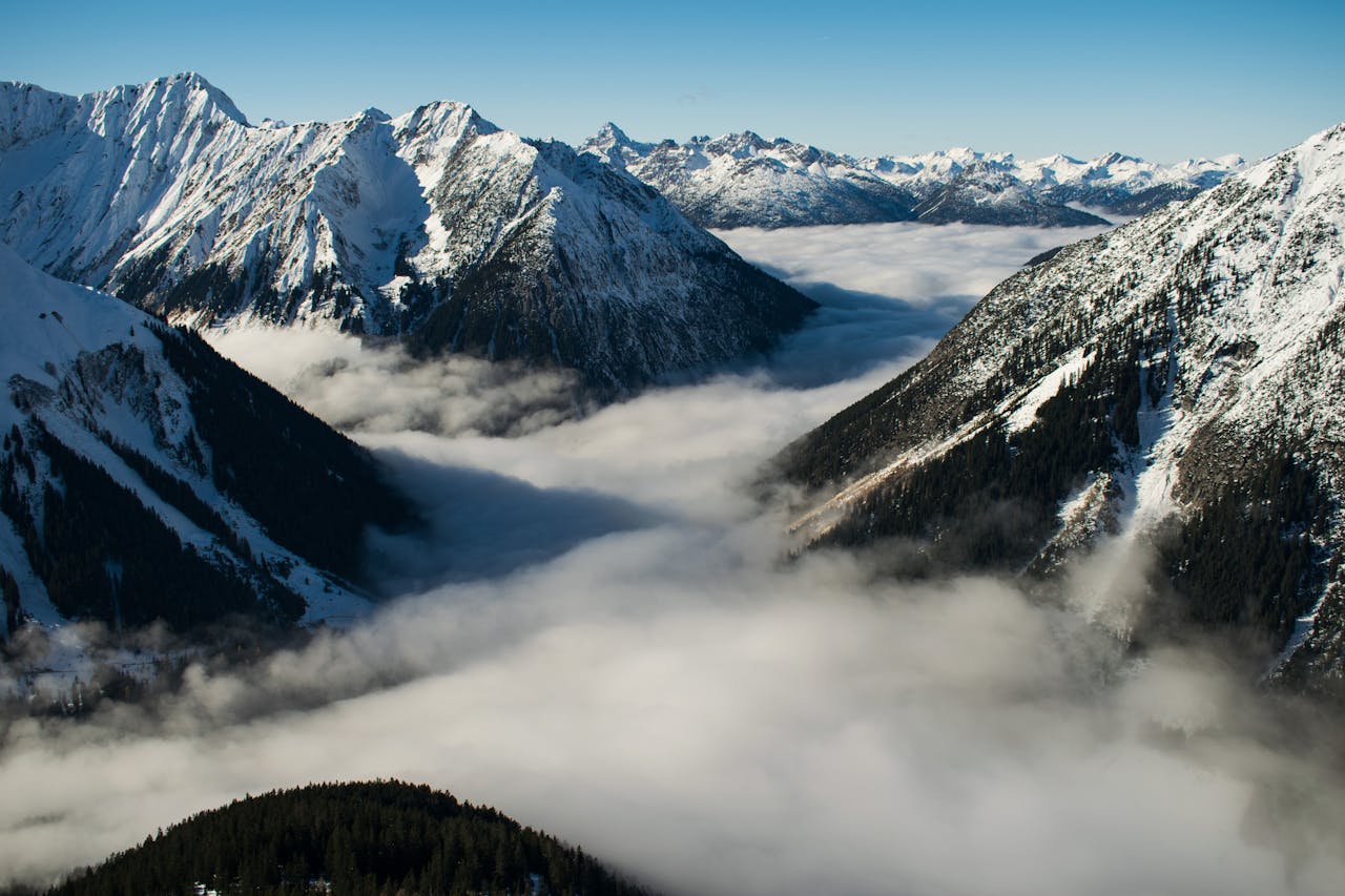 Services Majestic snow-covered mountains in Tirol, Austria with clouds and fog enveloping the valleys.